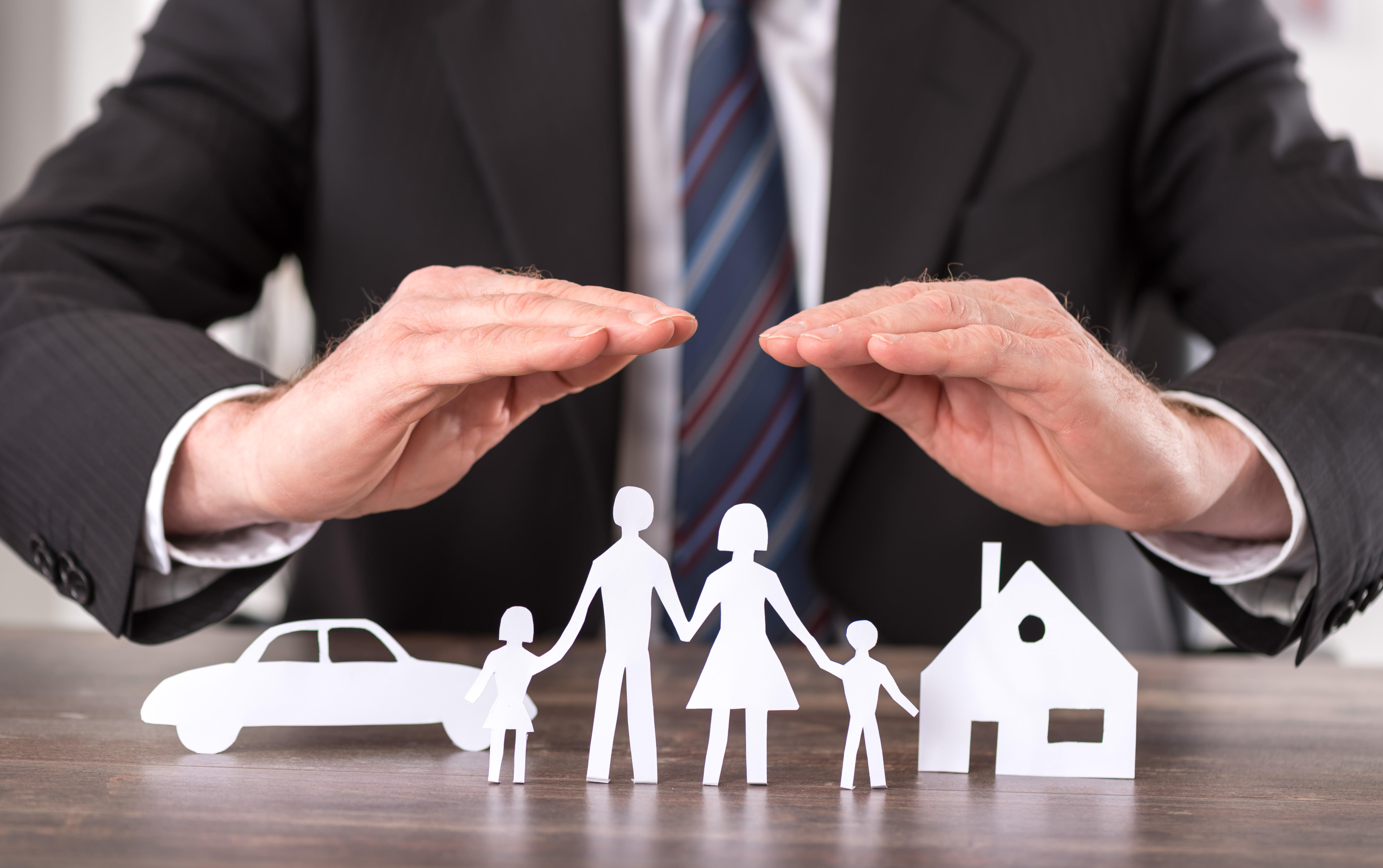 Hands covering cutouts of car, family, and house